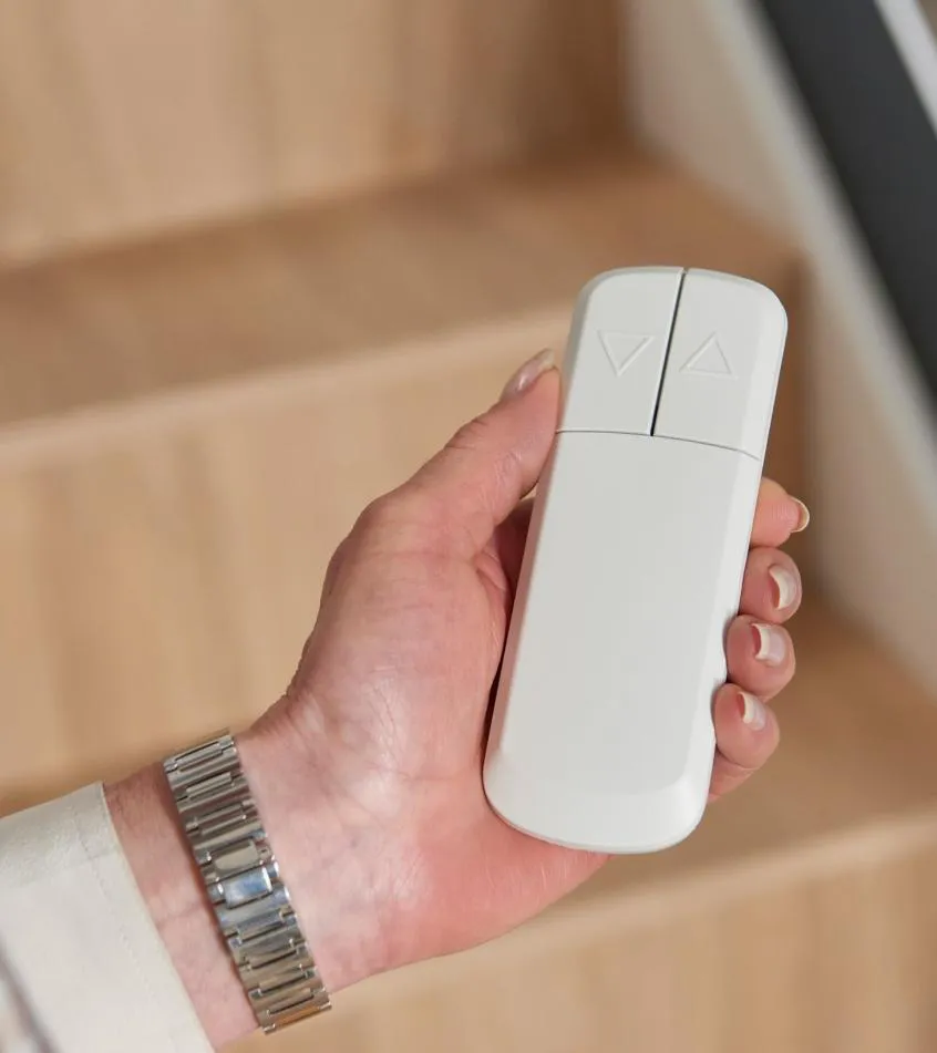 Hand holding a slim HomeGlide stairlift remote control