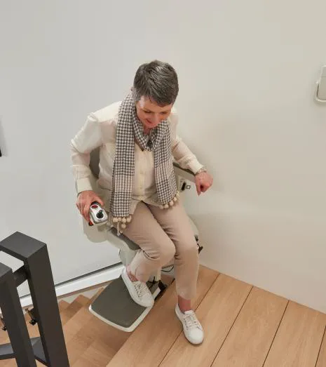Woman getting off a HomeGlide stairlift with the seat swivelled at the top of the stairs